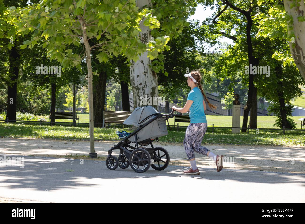 Frau joggt mit Kinderwagen in einem Stadtpark Stockfoto