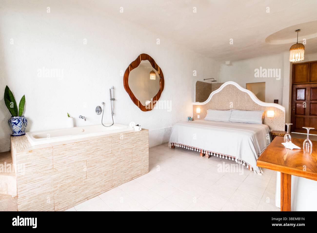 Ein einladendes Hotelzimmer in Cozumel, das in neutralen Farben und modernen Möbeln eingerichtet ist, verfügt über ein einzigartiges Bad mit eingebauter Badewanne, A Stockfoto