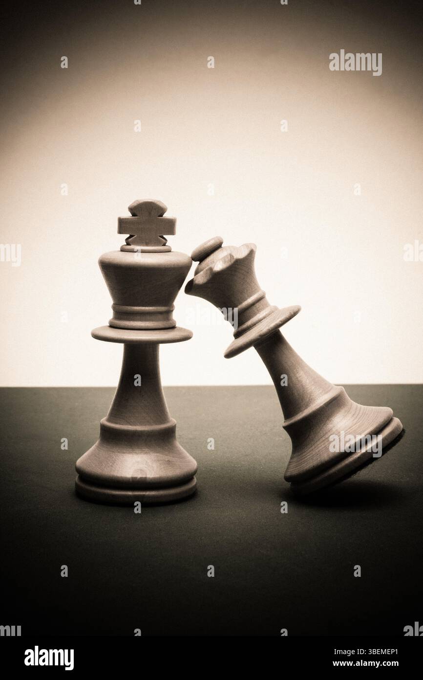 Zwei Schachfiguren stehen geneigt vor einem schlichten Hintergrund und symbolisieren einen heftigen Kampf der Vernunft. Das zeitlose Spiel steht für Strategie Stockfoto