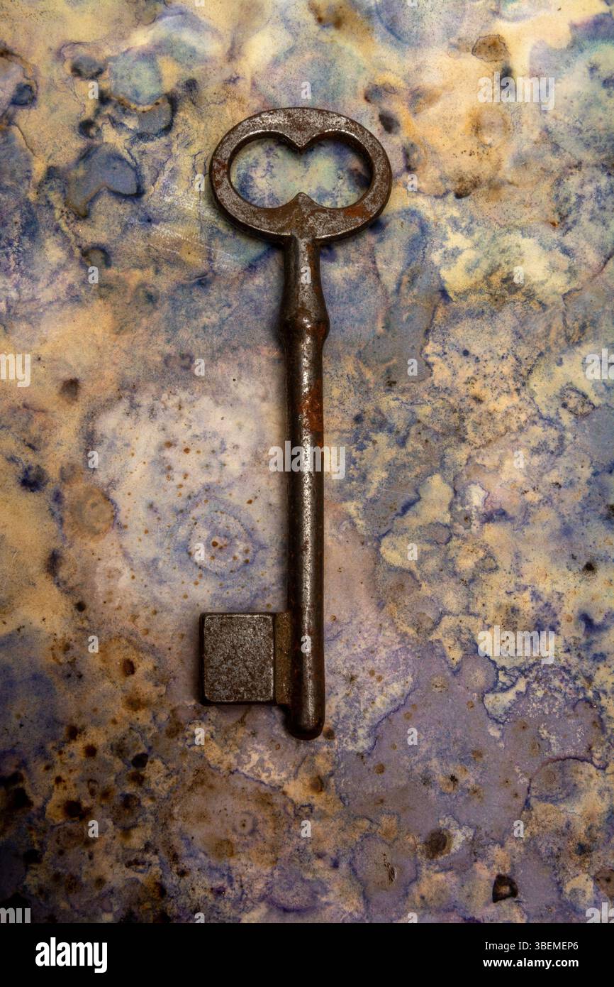 Ein alter Schlüssel liegt vor einem blau-beigen Hintergrund, der seinen Rost und Verschleiß zum Ausdruck bringt. Stockfoto Ein alter Schlüssel liegt vor einem blau-beigen Hintergrund, der seinen Rost und Verschleiß zum Ausdruck bringt. Stockfoto