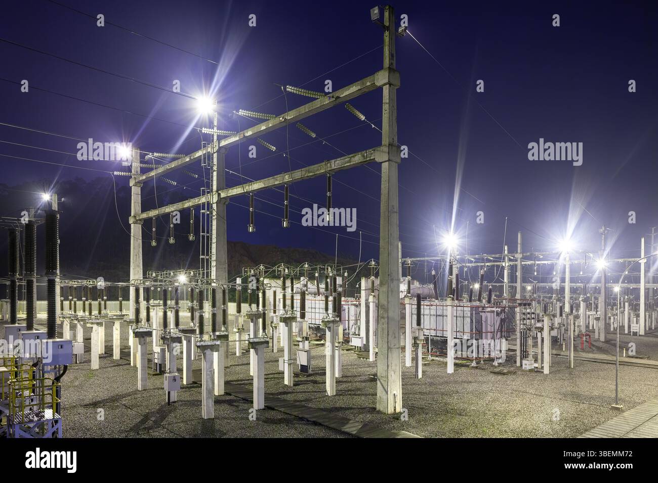 Elektrische Umspannstation bei Nacht, beleuchtet mit hellen Lichtern. Stockfoto