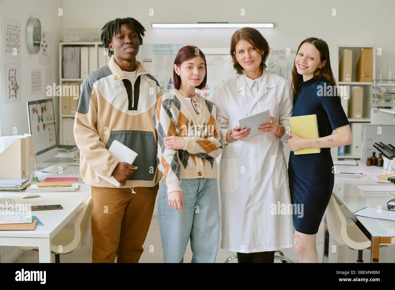 Gruppe von Studenten, die im Büro stehen und Tablets und Notebooks halten, die Zusammenarbeit und Teamarbeit zeigen. Schaffen Sie eine einladende Umgebung mit Stockfoto