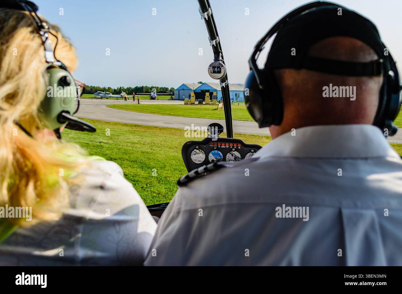 Hubschrauberinnenraum am Regionalflughafen Brockville mit männlichem Piloten und weiblichem Passagier mit Sichtschutz im Fokus Stockfoto