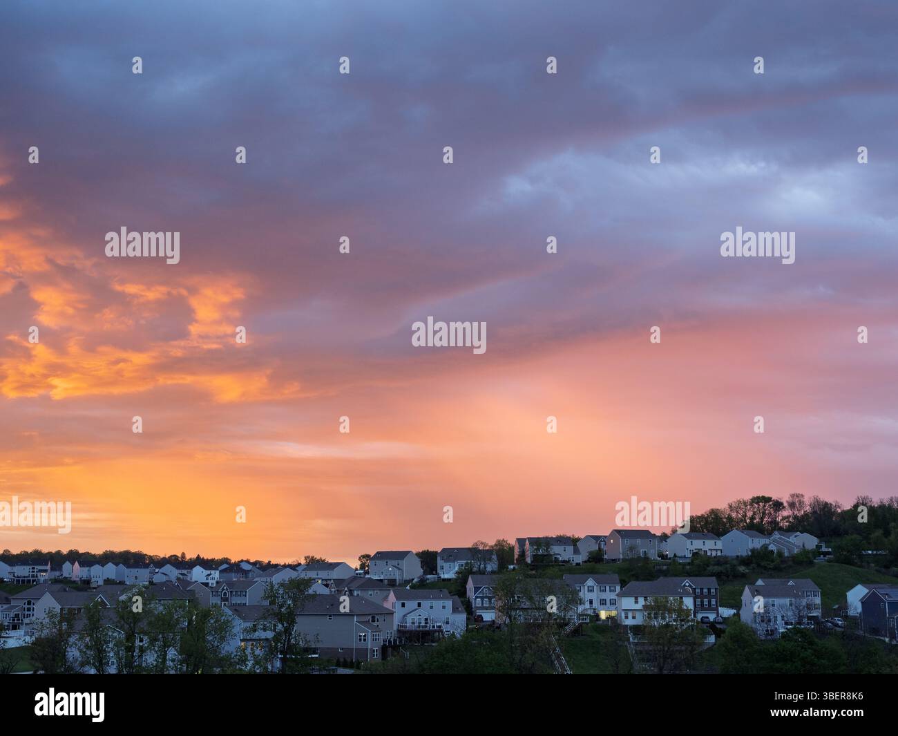 Der Himmel leuchtet während des Sonnenaufgangs in leuchtenden Orange- und Rosa-Tönen über Häusern in einem Wohnviertel in der Nähe von Pittsburgh. Stockfoto