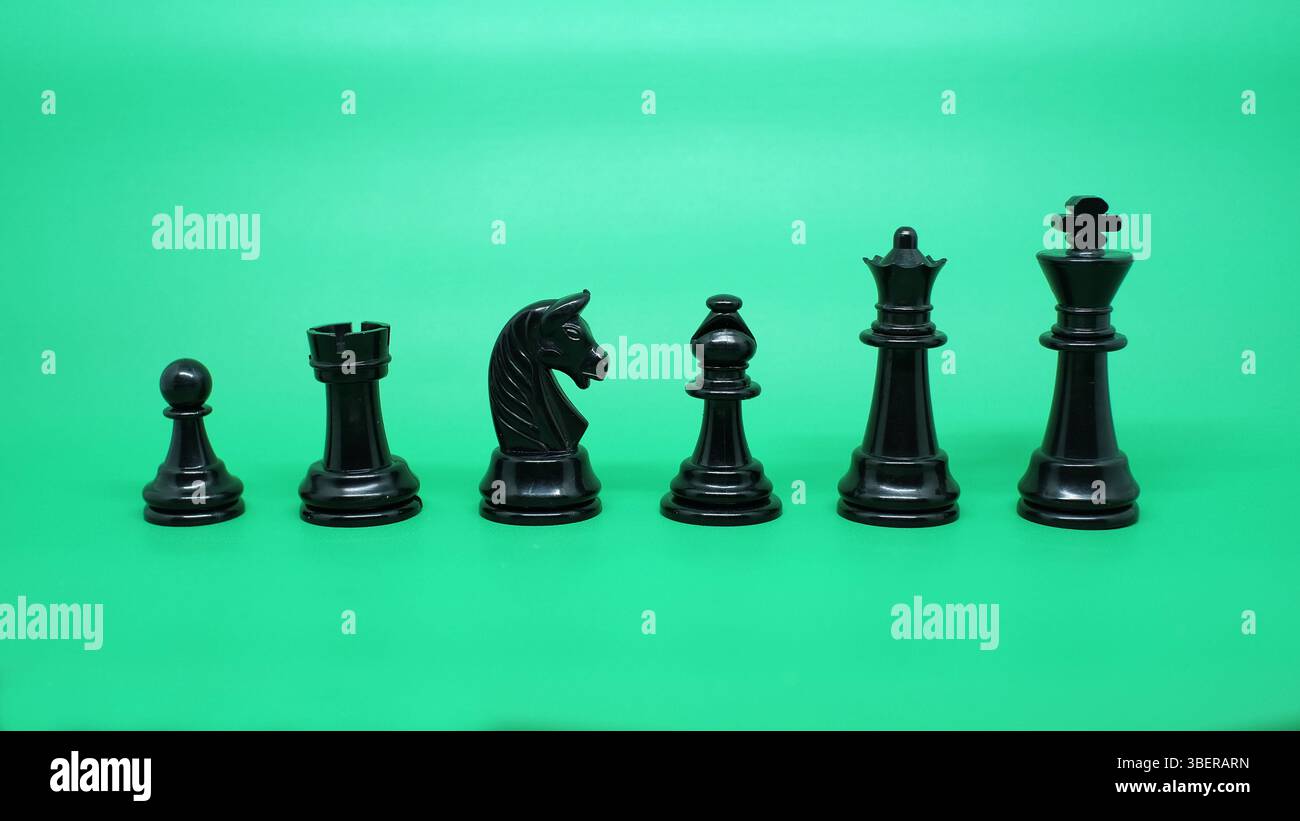 Das Arrangement von Schachfiguren, die von Schachfiguren, Bäumen, Rittern, Bischöfen, Königinnen, und Könige isoliert auf einem Grün. Stockfoto