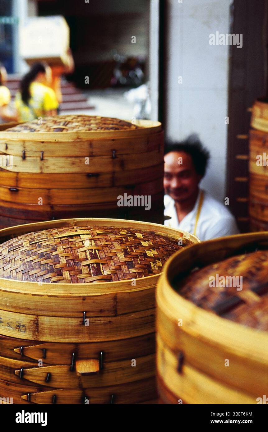 Ein Koch, der von traditionellen Bambusdampfern in einem kleinen Restaurant in Kaifeng, Provinz Henan, China sitzt. Stockfoto
