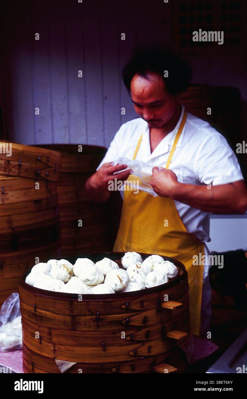 Ein Koch, der von traditionellen Bambusdampfern in einem kleinen Restaurant in Kaifeng, Provinz Henan, China sitzt. Stockfoto