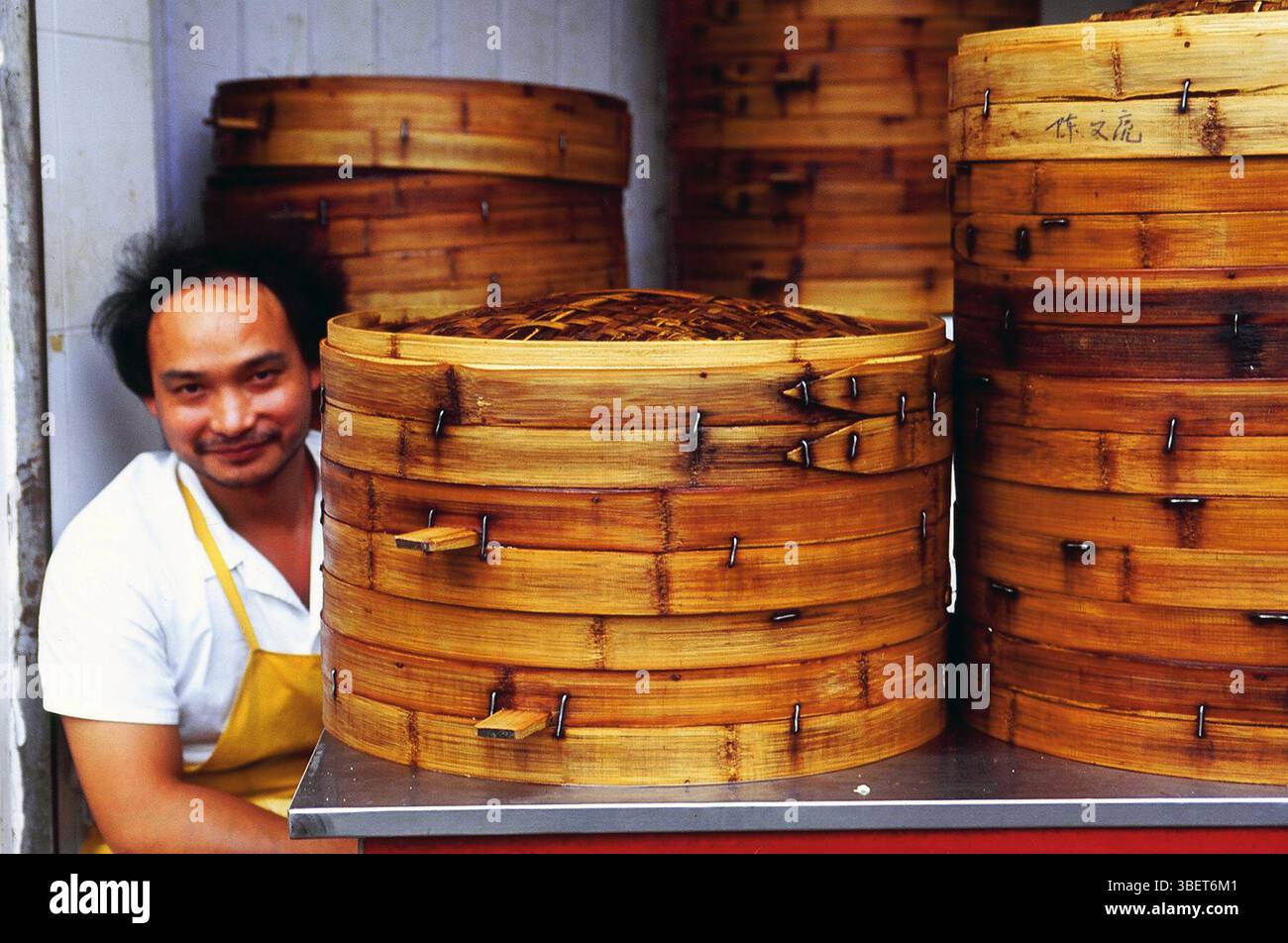 Ein Koch, der von traditionellen Bambusdampfern in einem kleinen Restaurant in Kaifeng, Provinz Henan, China sitzt. Stockfoto