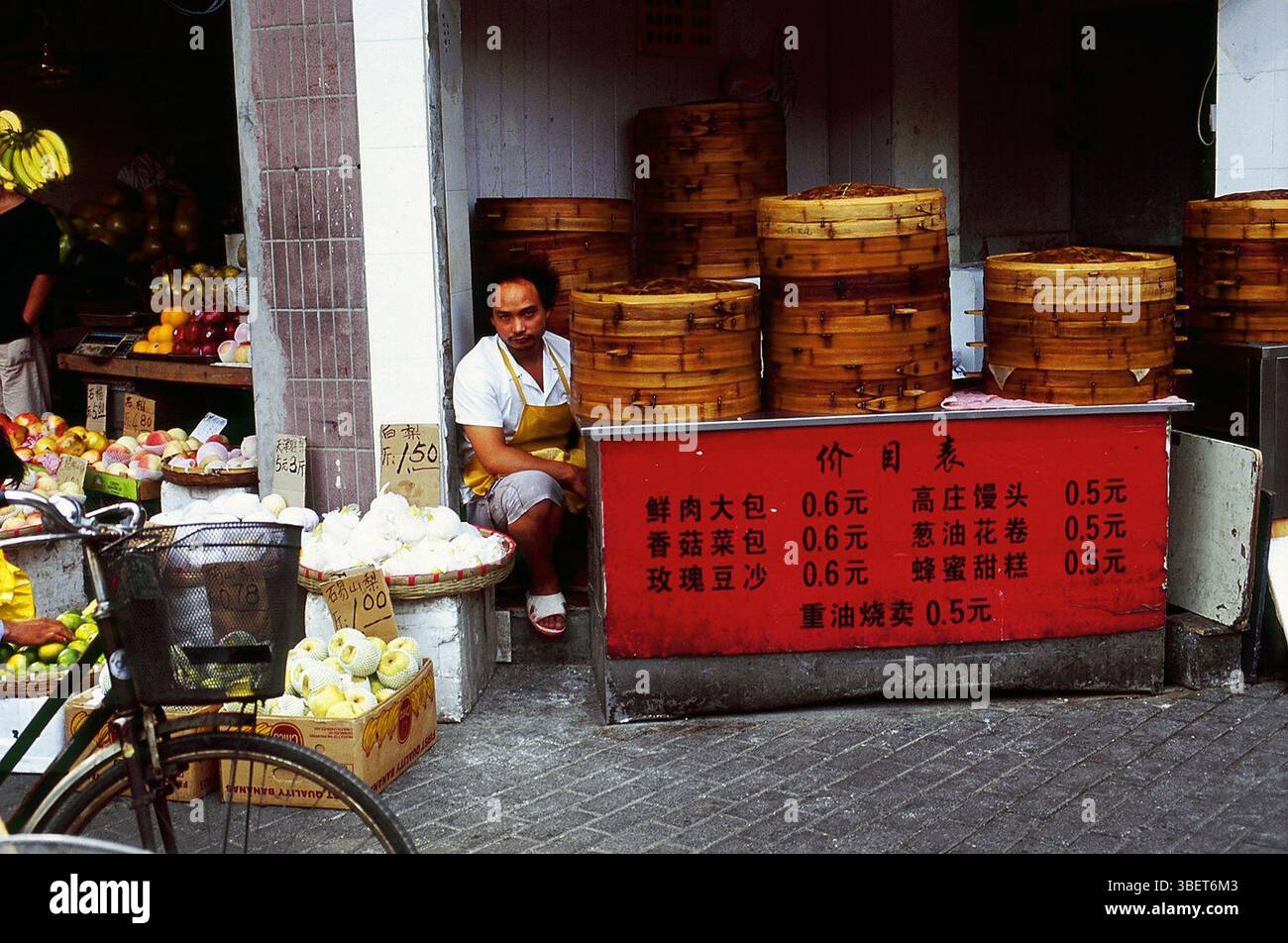 Ein Koch, der von traditionellen Bambusdampfern in einem kleinen Restaurant in Kaifeng, Provinz Henan, China sitzt. Stockfoto