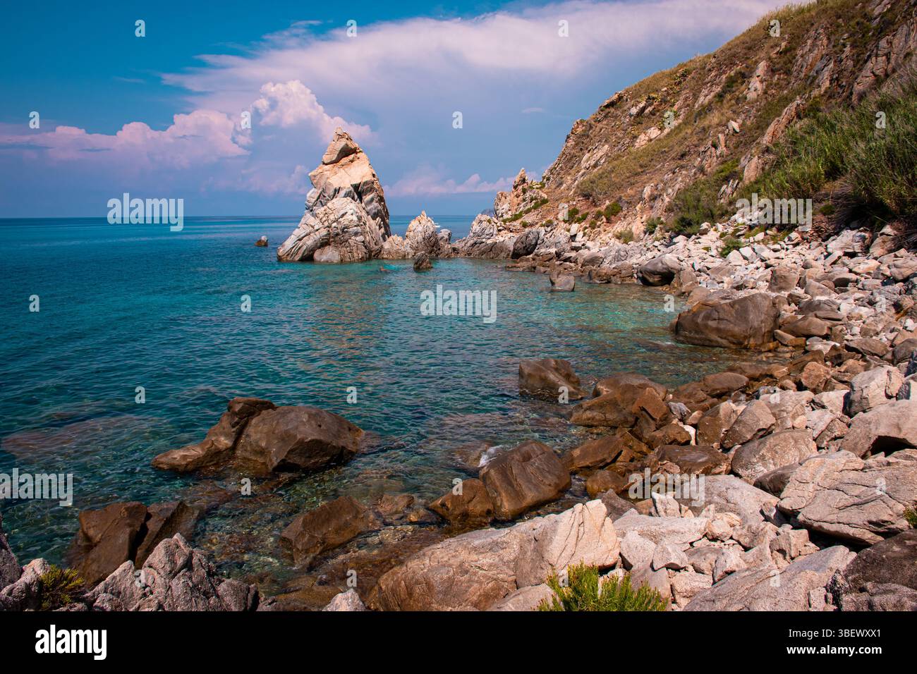 Felsige Klippen tauchen in das kristallklare Wasser des kalabrischen Meeres ein und bieten einen atemberaubenden Blick auf die Küste unter der Wärme der mediterranen Sonne Stockfoto