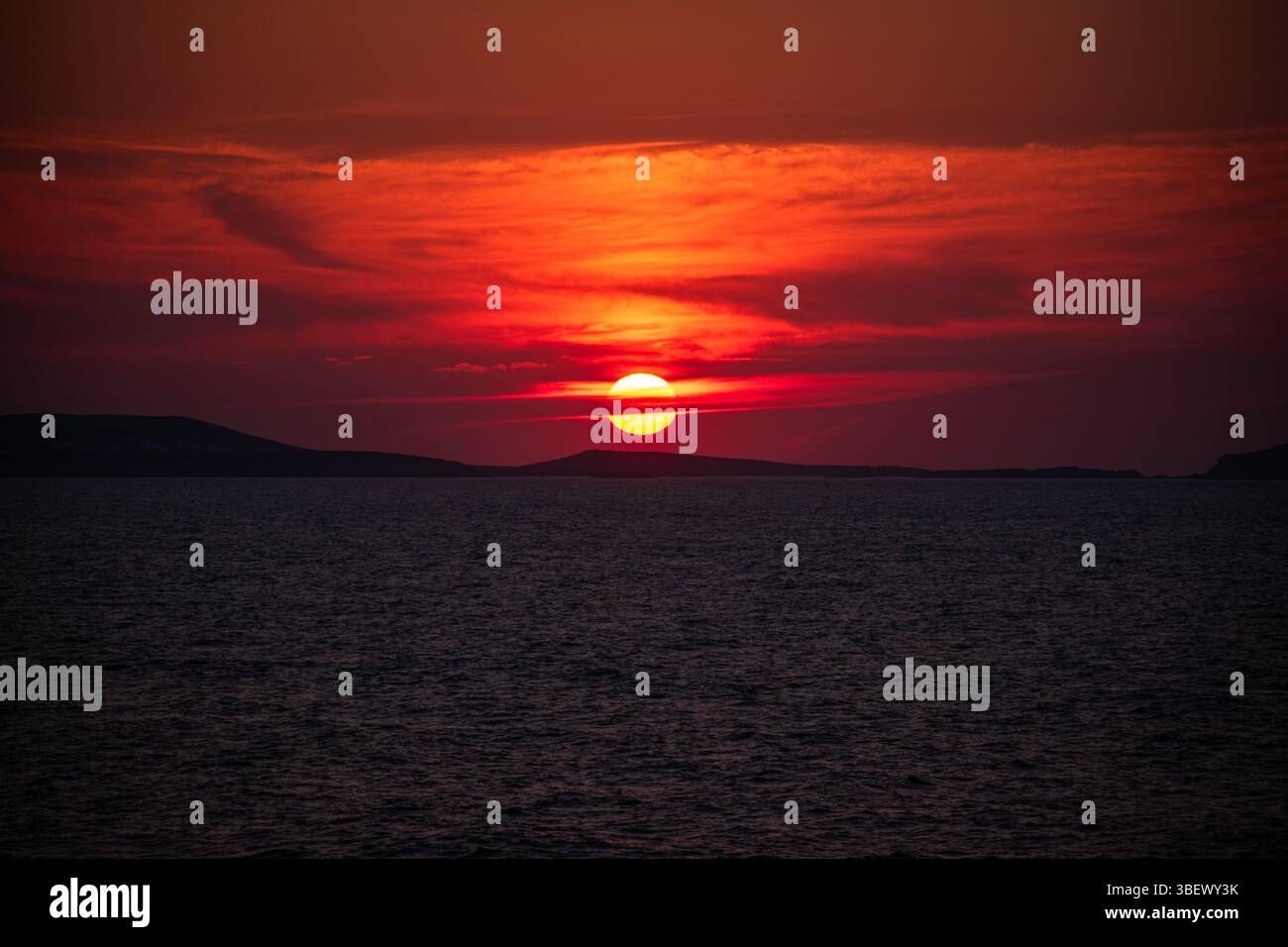 Sonnenuntergang über Piran, wo sich die goldene Sonne auf der ruhigen Adria spiegelt und den Horizont mit warmem Licht und friedlicher Schönheit übermalt. Stockfoto