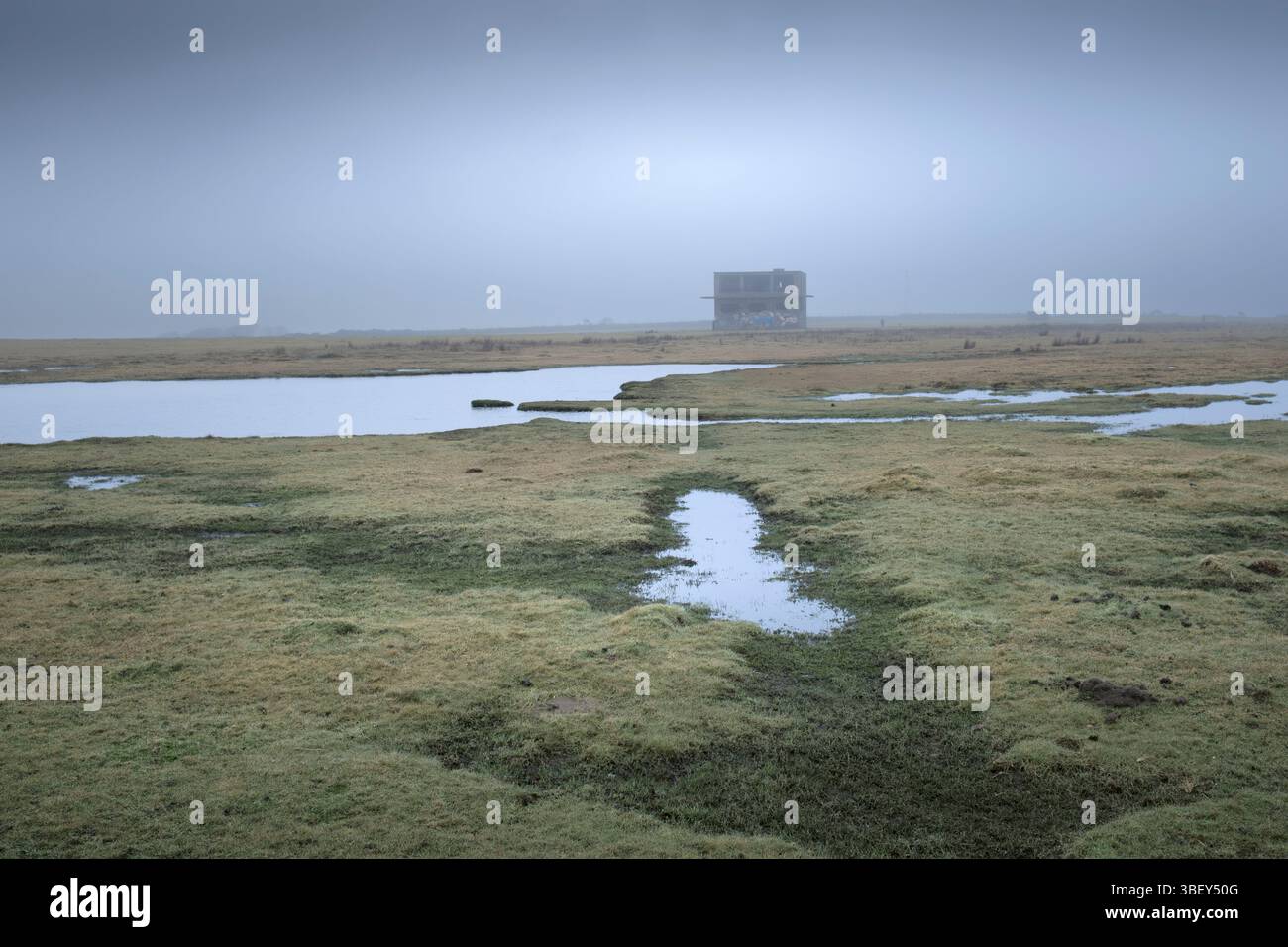Nebel und Nebel umhüllen das sumpfige, überflutete Gelände und die verlassenen historischen Überreste des alten Kontrollturms auf dem stillgelegten RAF Davidstow Moor Flugplatz. Stockfoto