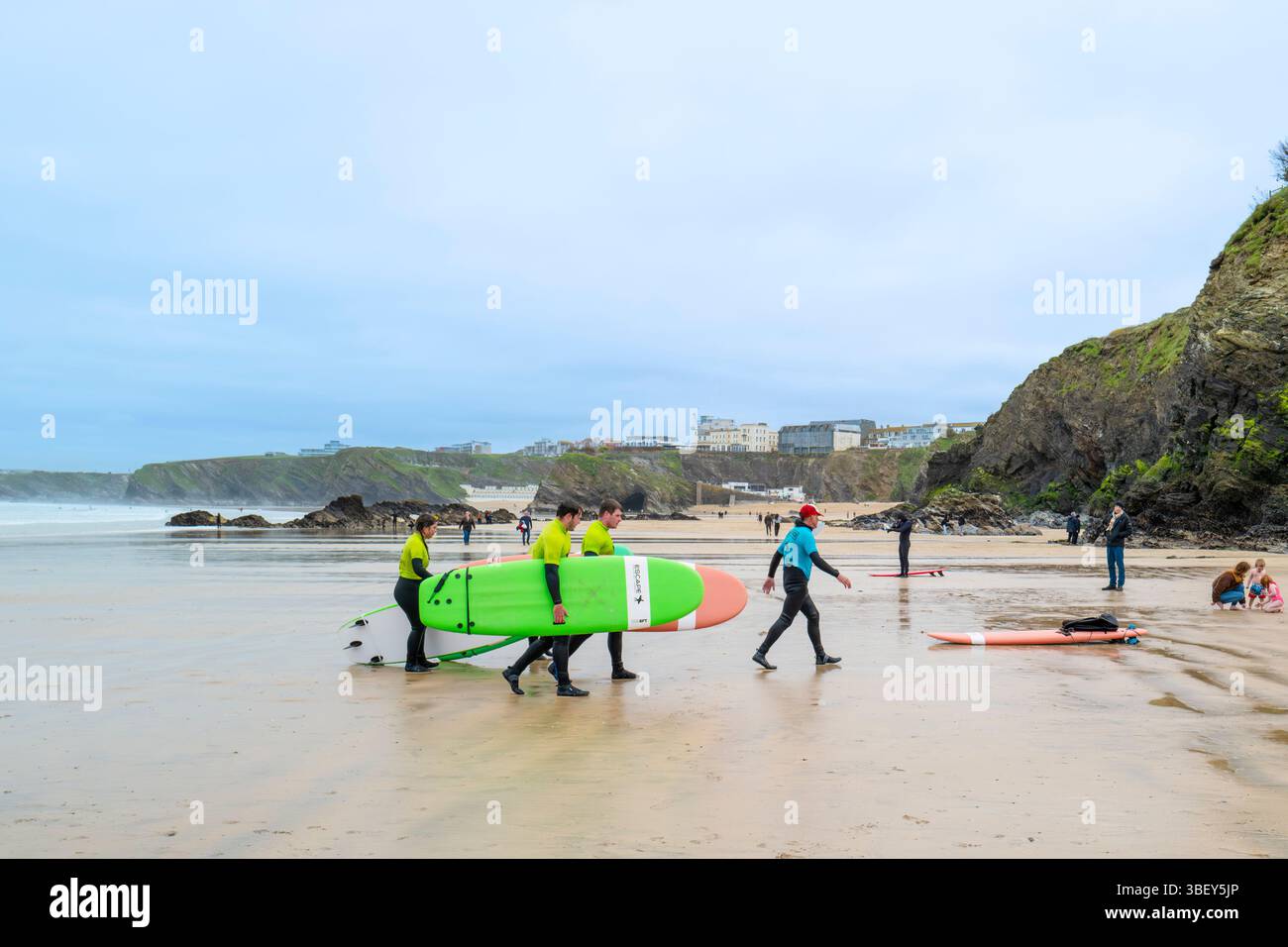 Ein Surflehrer der Escape Surf School geht mit einer Gruppe von Surfern am Towan Beach in Newquay in Cornwall, Großbritannien. Stockfoto