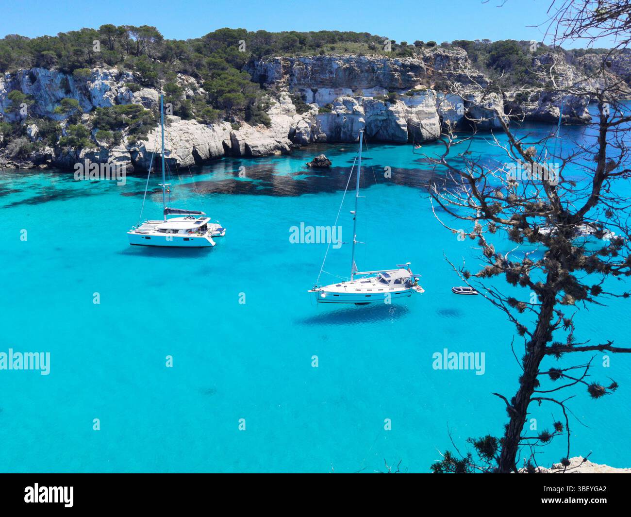 Cala Macarella, türkisfarbenes Wasser, transparentes Meer, schwimmende Yachten, Kiefern, Balearen, Menorca Strand, Mittelmeerküste, kristallklares Wasser - Smartphone-aufgenommenes Stockfoto