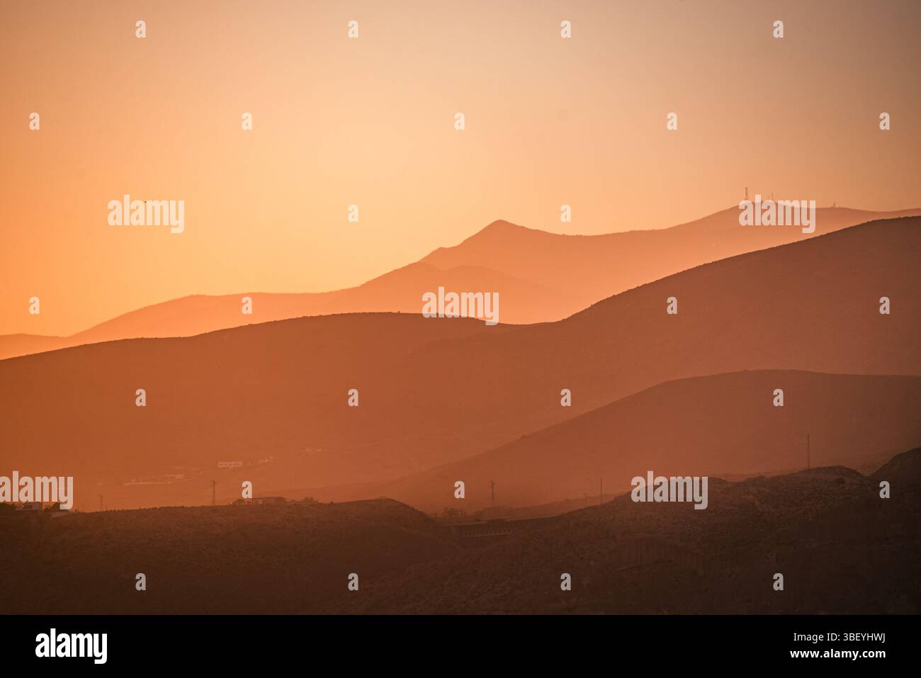 Goldene Farbtöne bedecken die sanften Berge von AlmerAdz?A, Spanien, während die untergehende Sonne einen traumhaften, mehrschichtigen Silhouetteneffekt erzeugt Stockfoto