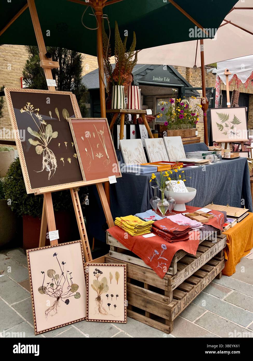 Ein Marktstand mit gerahmten getrockneten Blumen auf der Spring Fair im Rahmen der RHS Chelsea Flower Show in Chelsea, London, England, Großbritannien. - Smartphone-aufgenommenes Stockfoto