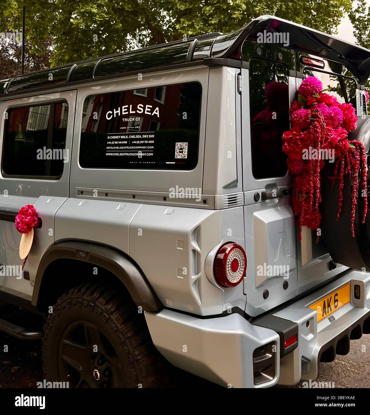Ein silbernes Auto mit frischen rosafarbenen Blumen im Rahmen der RHS Chelsea Flower Show in Chelsea, London, England, Großbritannien, Europa im Frühjahr. - Smartphone-aufgenommenes Stockfoto