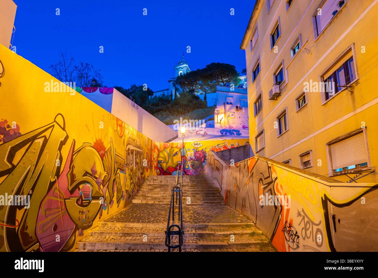 Blick auf farbenfrohe Graffiti und Stufen, die zur Kirche unserer Lieben Frau von Gnade in der Abenddämmerung im Alfama-Viertel, Lissabon, Portugal, Europa führen Stockfoto