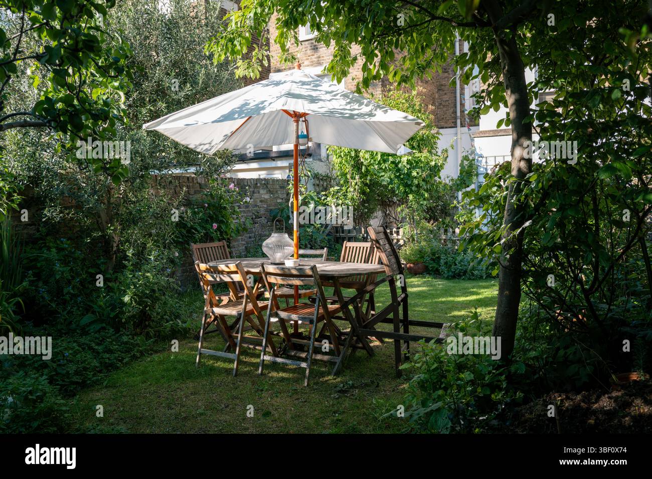Gartentisch und Sonnenschirm im echten Garten Stockfoto