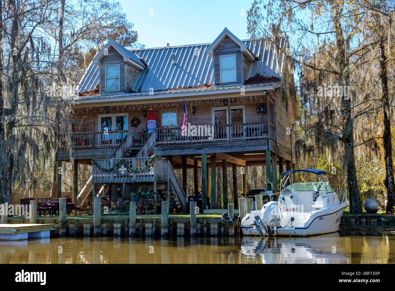 Ein Bayou-Haus ist für die Feiertage dekoriert, mit einem Boot in der Nähe für einfachen Zugang zum Wasser. Stockfoto