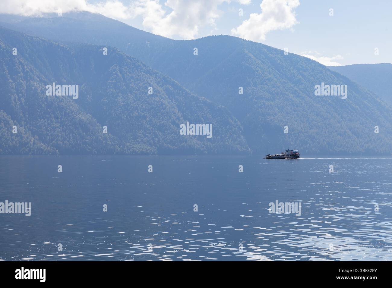 Eine kleine Fähre mit Passagieren und Autos an Deck segelt an einem sonnigen Sommertag den Teletskoye See, Foto der sibirischen Landschaft Stockfoto