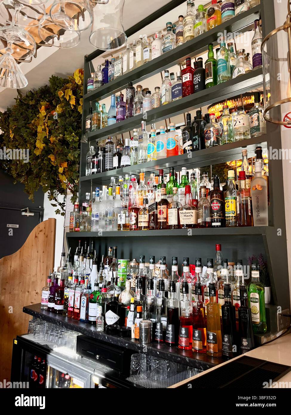 Eine ästhetische Präsentation von Glasalkoholflaschen hinter einer Bar im Herzen von Oxford City, England, Großbritannien, Europa an einem sonnigen Frühlingstag. - Smartphone-aufgenommenes Stockfoto