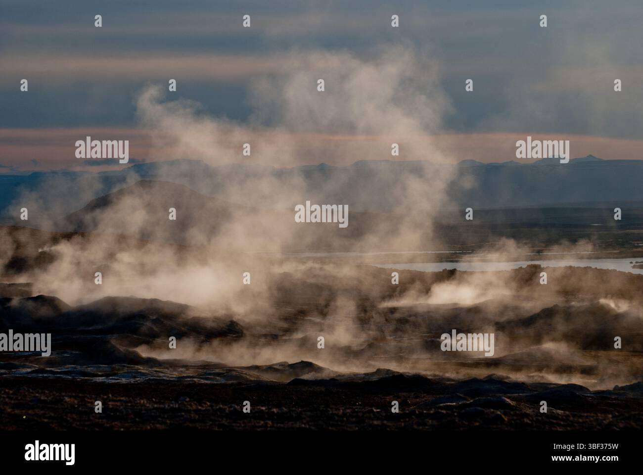 Geothermiegebiet Namafjall Hverir. Dampf steigt aus Islands geothermischen Feldern auf, während der warme Sonnenuntergang die Landschaft färbt. Stockfoto