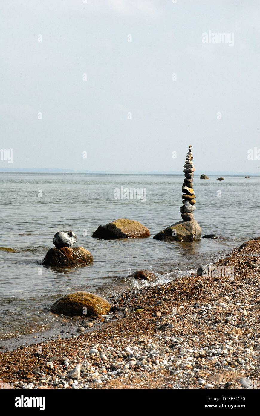 Steinformationen am Ostseestrand, gestapelte Felsbrocken im Wasser mit Kieselstein und Sandstrand Stockfoto
