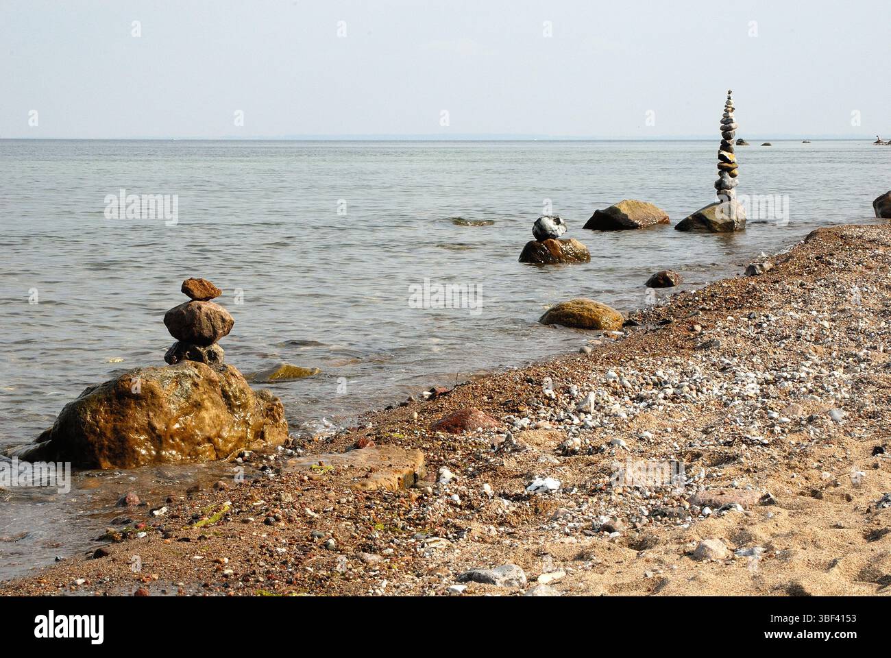 Steinformationen am Ostseestrand, gestapelte Felsbrocken im Wasser mit Kieselstein und Sandstrand Stockfoto
