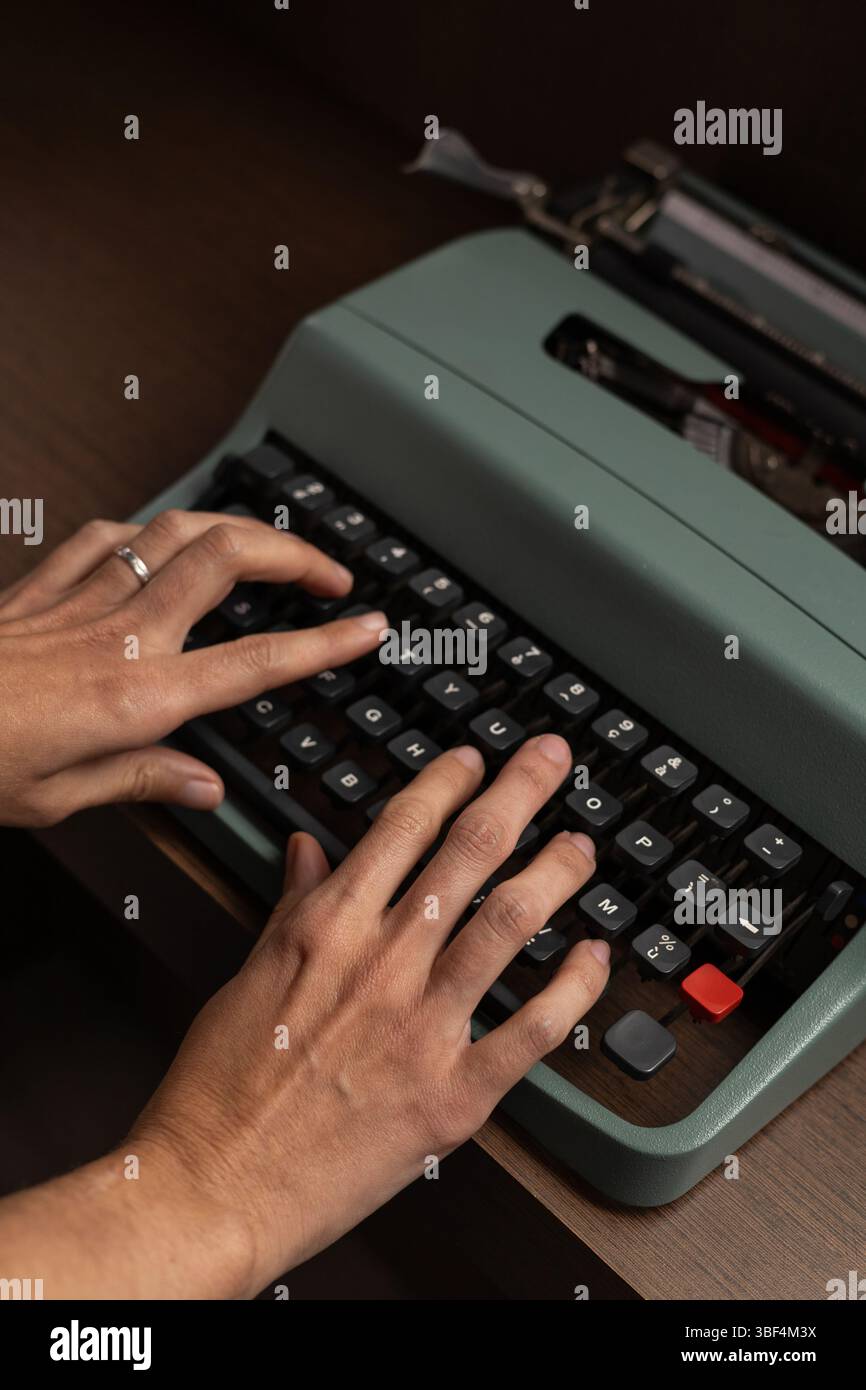 Nahaufnahme der Hände, die auf einer Vintage-Schreibmaschine tippen, um die Haptik klassischer Schreibweise zu erfassen. Dieses eindrucksvolle Bild symbolisiert Kreativität, Nostalgie Stockfoto