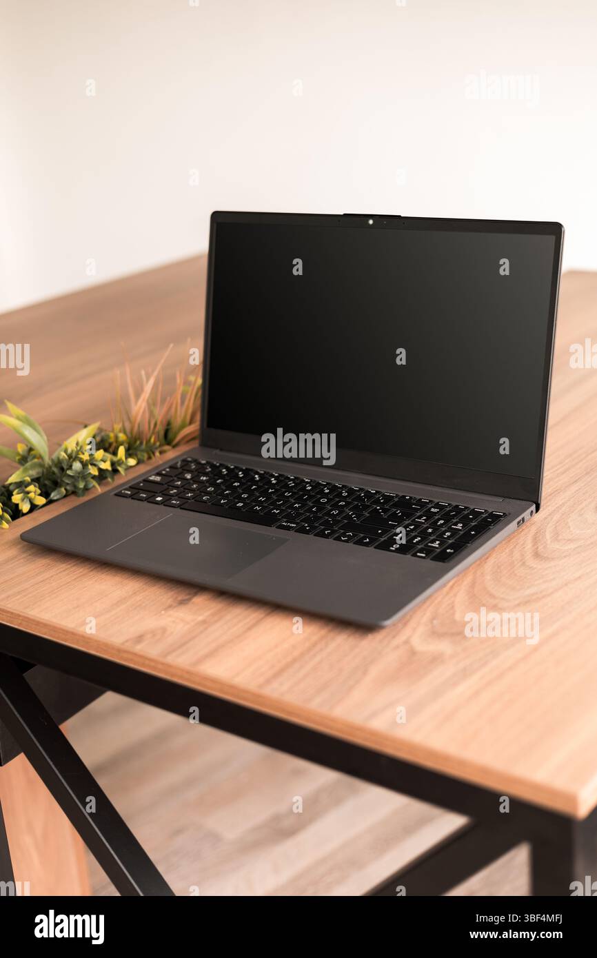 Stilvolle Schreibtischeinrichtung mit einem modernen Notebook als Mittelpunkt, das Produktivität, Einfachheit und elegante, technisch ausgerichtete Ästhetik des Arbeitsplatzes hervorruft. Stockfoto
