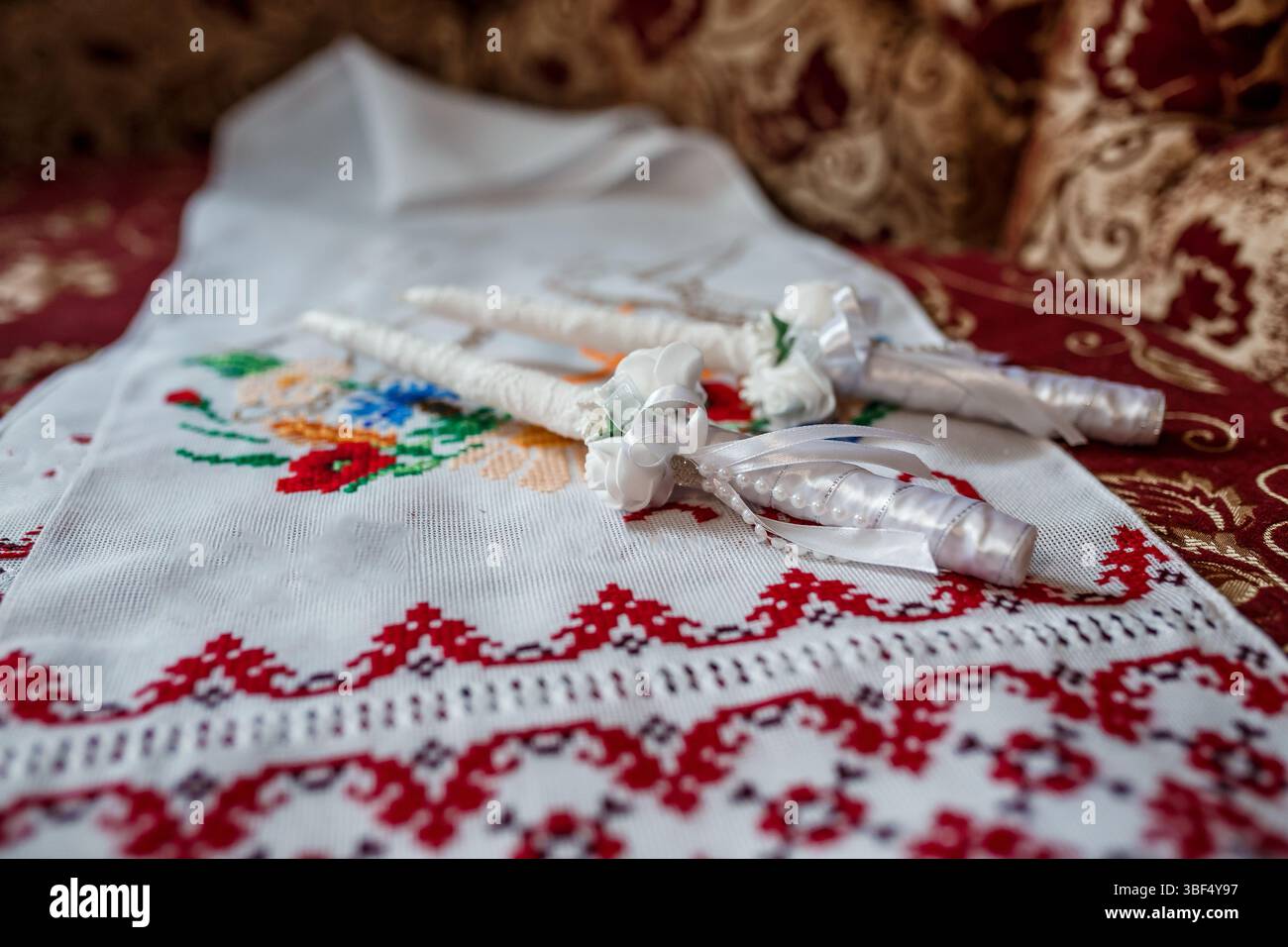 Dieses Bild zeigt eine wunderschöne rumänische Hochzeitstradition mit einem weißen, aufwendig gestickten Tuch, das Hochzeitskronen mit weißen ri zeigt Stockfoto