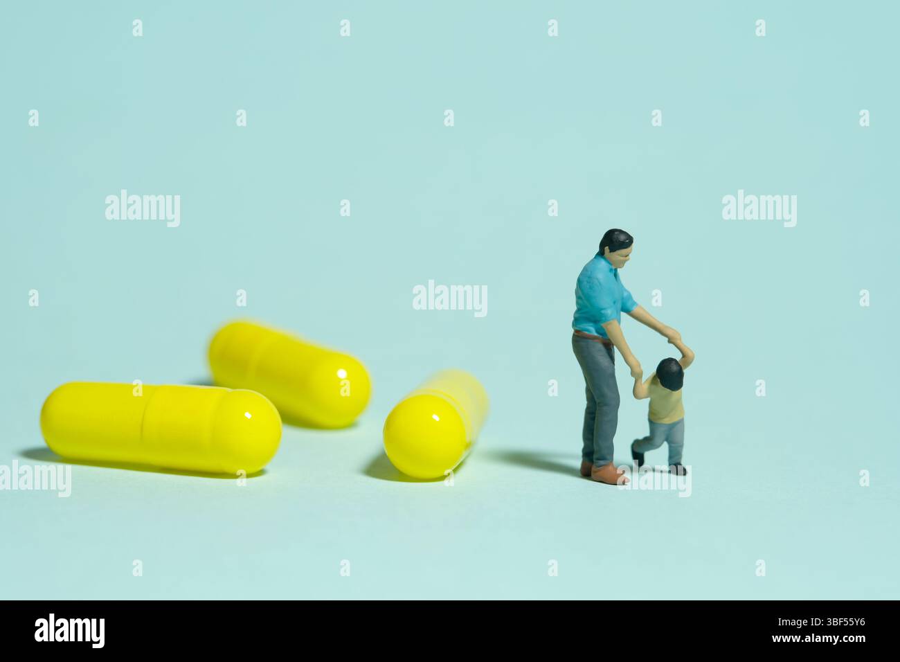 Miniatur-Menschen-Spielzeug-Figuren-Fotografie. Arzneimittelmedizin lehnt Konzept ab. Ein Vater und Sohn stehen neben Medizinpillen. Isolierter blauer Hintergrund. Ima Stockfoto