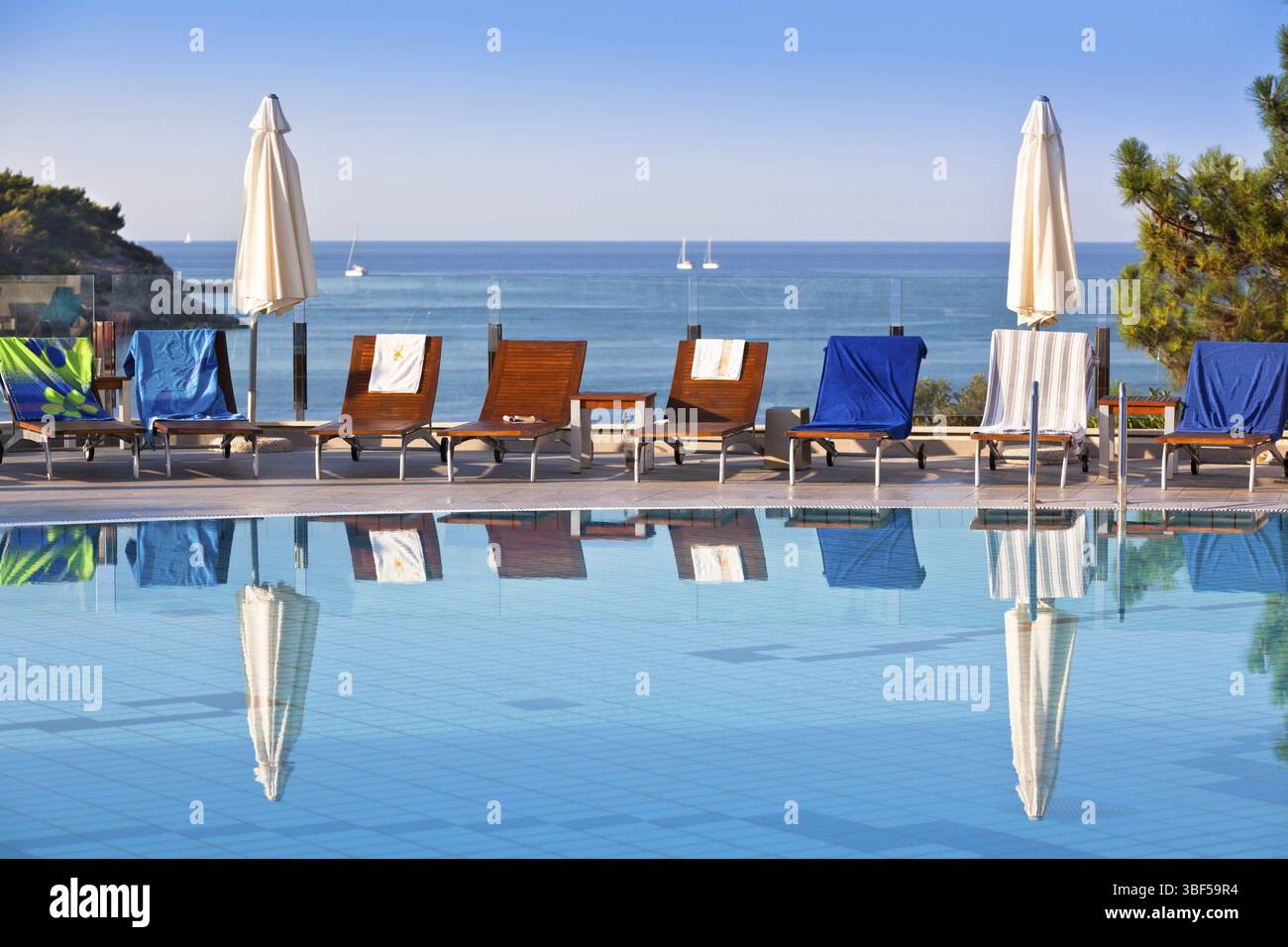 Sonnenliegen und Sonnenschirme am Pool an einem sonnigen Tag Stockfoto