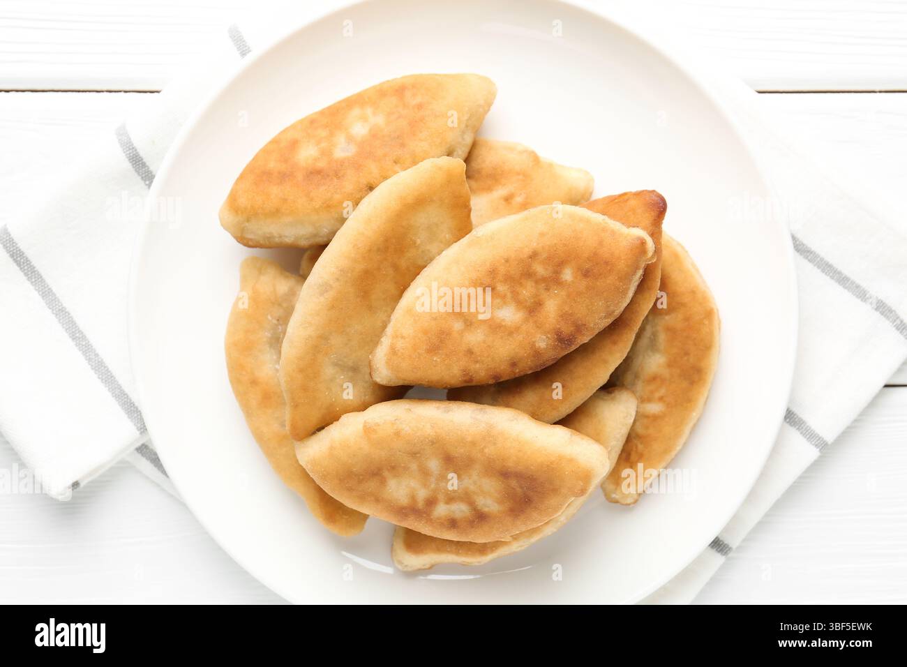 Köstliche gebratene Pyrizhky (gefüllte Kuchen) auf weißem Holztisch, Blick von oben Stockfoto Köstliche gebratene Pyrizhky (gefüllte Kuchen) auf weißem Holztisch, Blick von oben Stockfoto