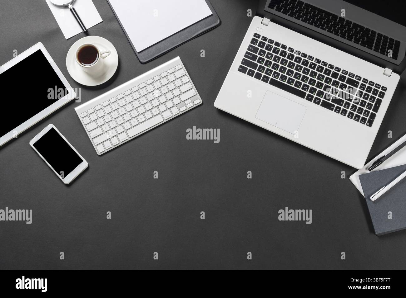 Draufsicht auf Designer-Arbeitsplatz mit modernen digitalen Geräten. Flaches, elegantes Design mit schwarzer Oberfläche und Kopierraum. Digitale Technologie und Mobilgeräte l Stockfoto