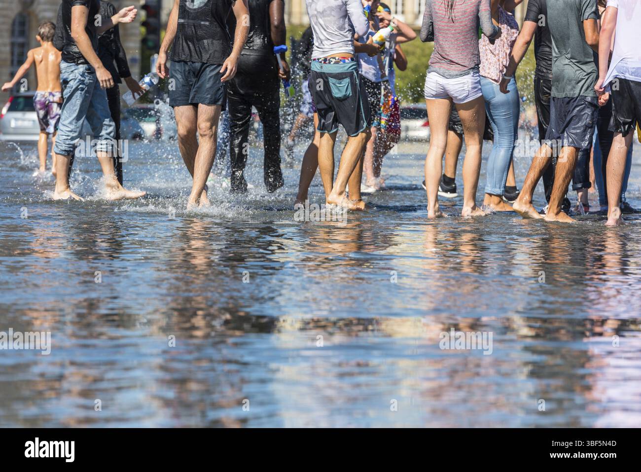 Leute, die sich in einem Spiegelbrunnen vor dem Place de la Bourse in Bordeaux, Frankreich, Europa amüsieren Stockfoto