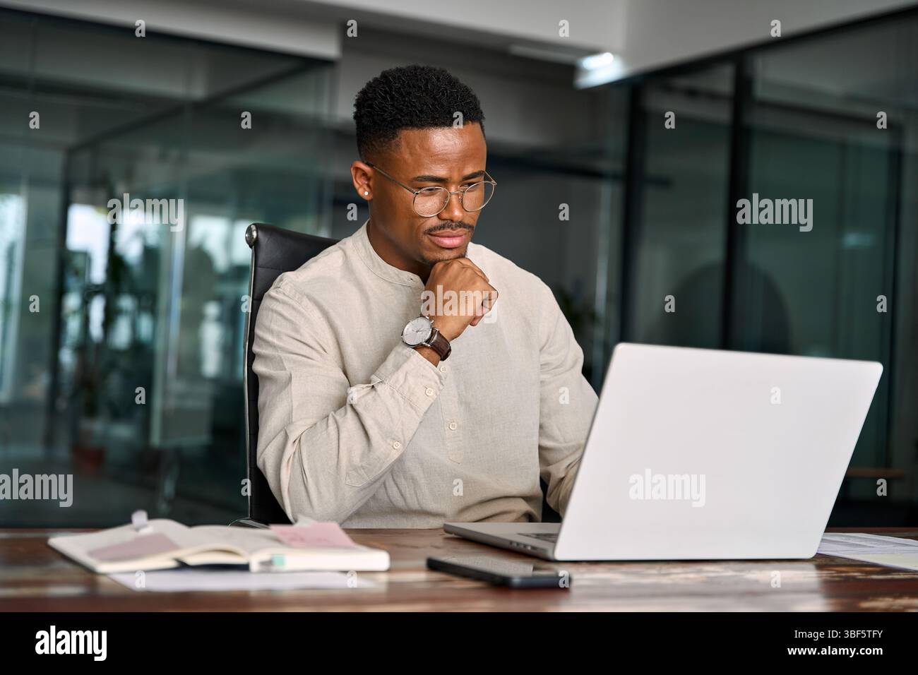 Ein beschäftigter afrikanischer Geschäftsmann denkt an Online-Investitionen und arbeitet an Laptops. Stockfoto