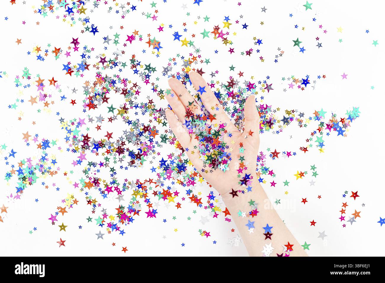 Hellen festlichen Farbe Konfetti Sterne funkelt mit Frau hand auf weißem Hintergrund. Kreative konzeptionelle Weihnachten Geburtstag Top View flat La Stockfoto