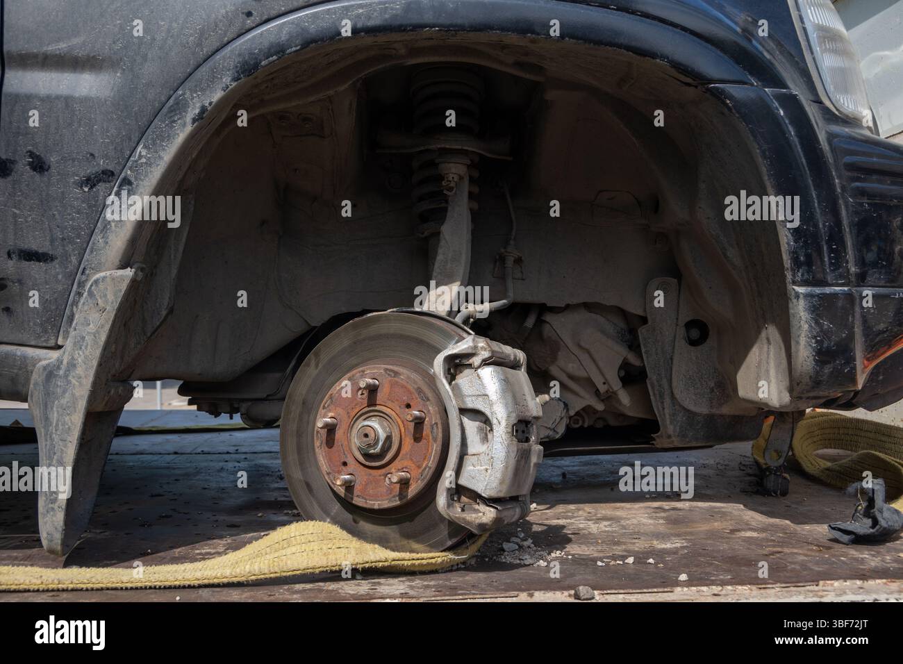 Freiliegende Bremsscheibe und Aufhängungssystem unter einem staubigen Radlauf. Fahrzeug-Wartungs- oder Reparaturkonzept bei Sonnenlicht Stockfoto