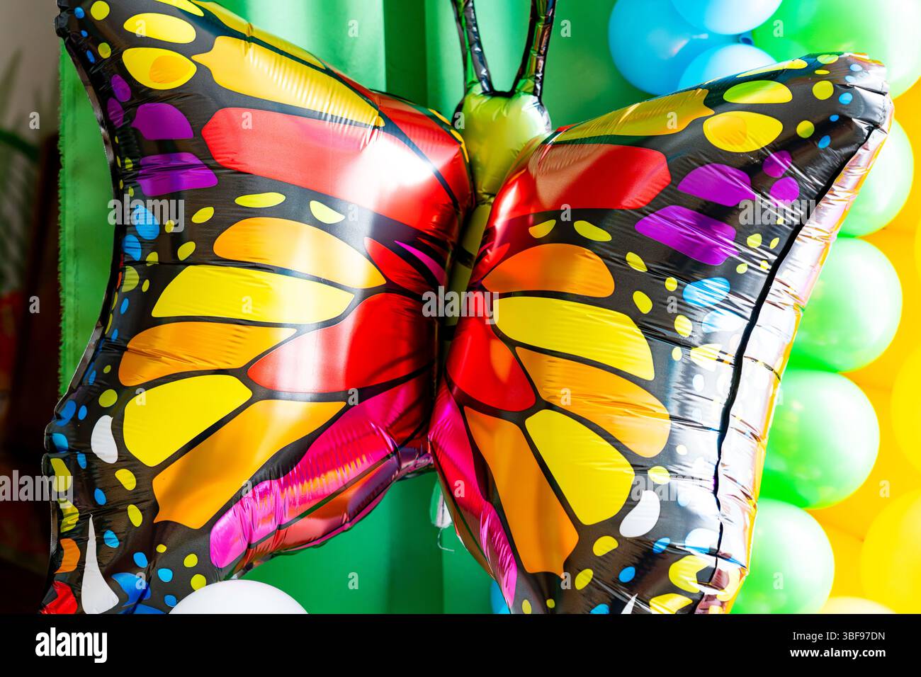 Ein großer, farbenfroher Schmetterlingsballon steht bei einer Feier im Mittelpunkt. Leuchtende Rot-, Gelb- und Schwarztöne erregen die Aufmerksamkeit der festlichen Dekora Stockfoto