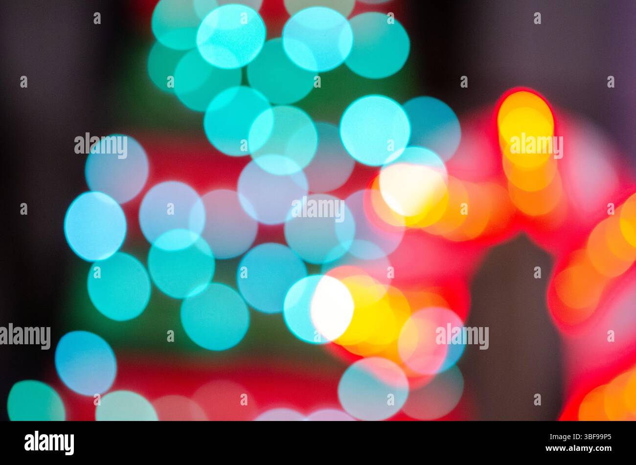 Leuchtende türkisfarbene und rote Bokeh-Lichter sorgen für festliche Weihnachtsstimmung, perfekt für Weihnachten oder Silvester-Themen und kreative Hintergründe. Stockfoto