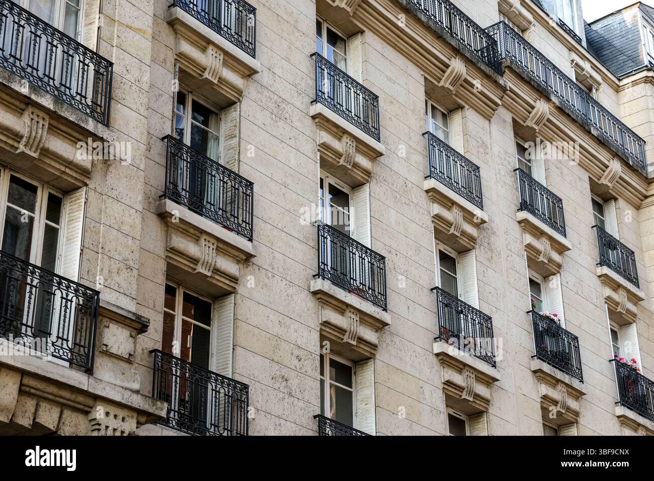 Eine Nahperspektive auf die Fassade eines klassischen Pariser Apartmenthauses, die die Steinkonstruktion und mehrere mit verzierten Fenstern hervorhebt Stockfoto