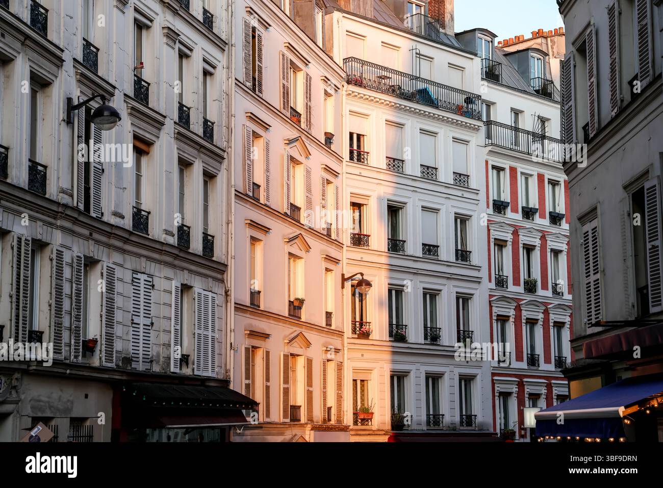 Die eleganten Pariser Gebäudefassaden und eine kopfsteingepflasterte Straße werden wunderschön vom warmen Glanz der goldenen Stunde beleuchtet, was den Klassiker unterstreicht Stockfoto