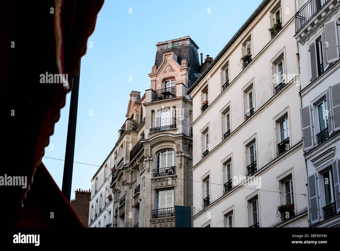 Eine flache Perspektive, die die Pracht typischer Pariser Apartmenthäuser in Richtung eines klaren blauen Himmels einfängt und betont Stockfoto