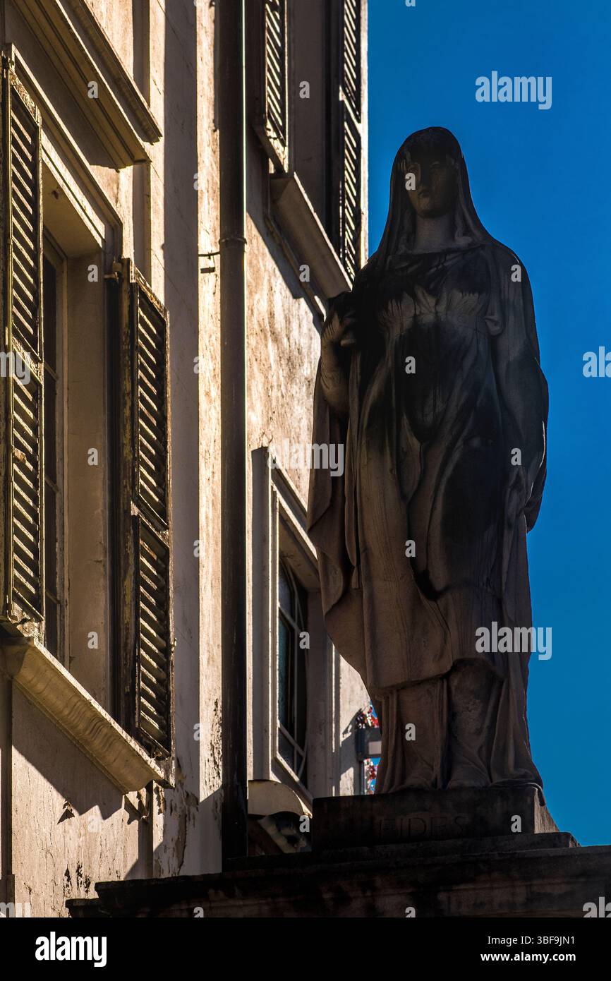Eine der Statuen, die den Weg zur Kathedrale von Saint-Lorenz in der Via Borghetto, Lugano, flankiert. Schweiz. Die Basis trägt die Inschrift FIDES (glaube in Laton) Stockfoto