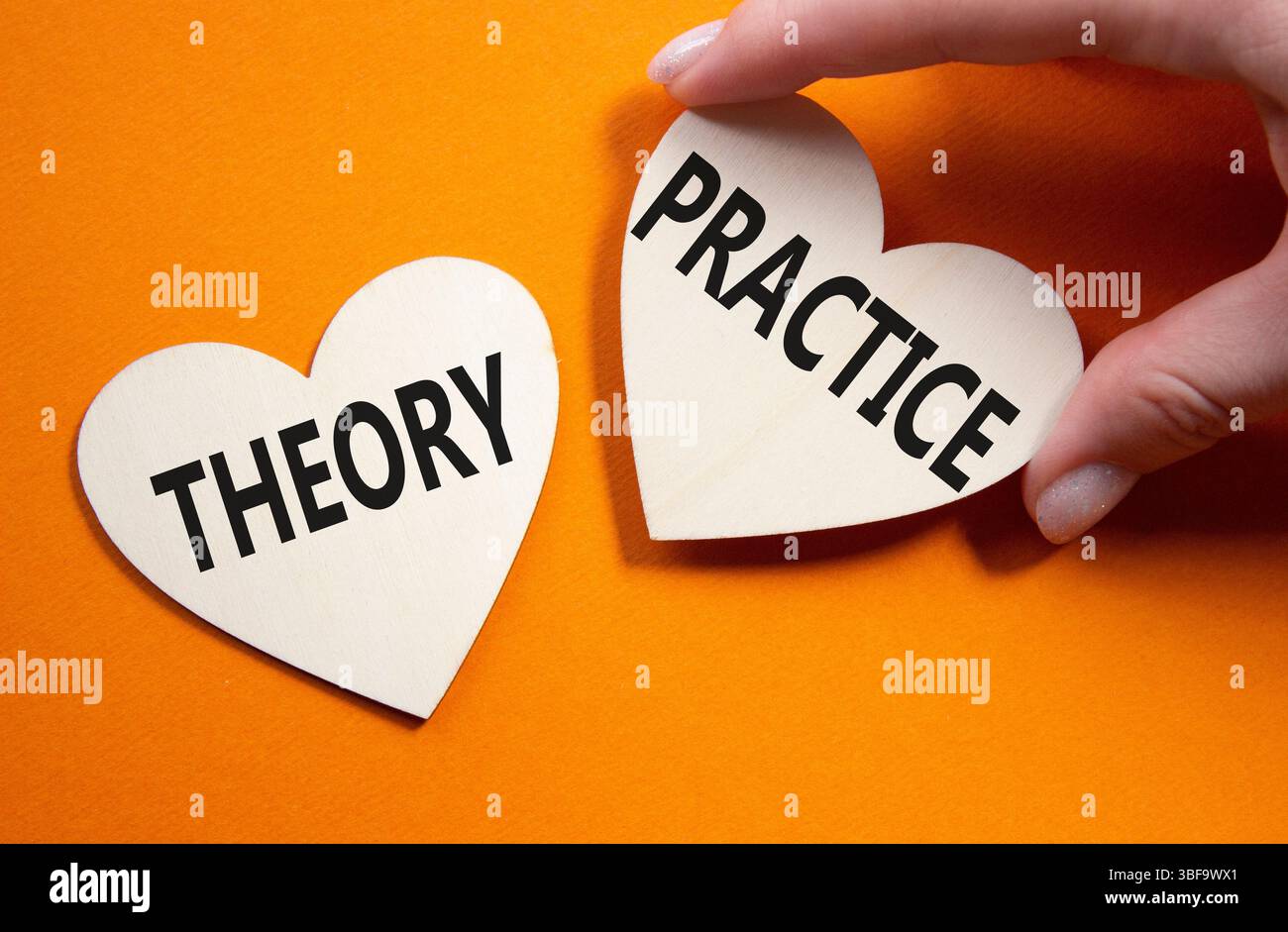 Theorie- oder Praxissymbol. Konzeptwort Theorie oder Praxis auf hölzernen Herzen. Geschäftsmann Hand. Wunderschöner orangefarbener Hintergrund. Business and Theory oder Pra Stockfoto
