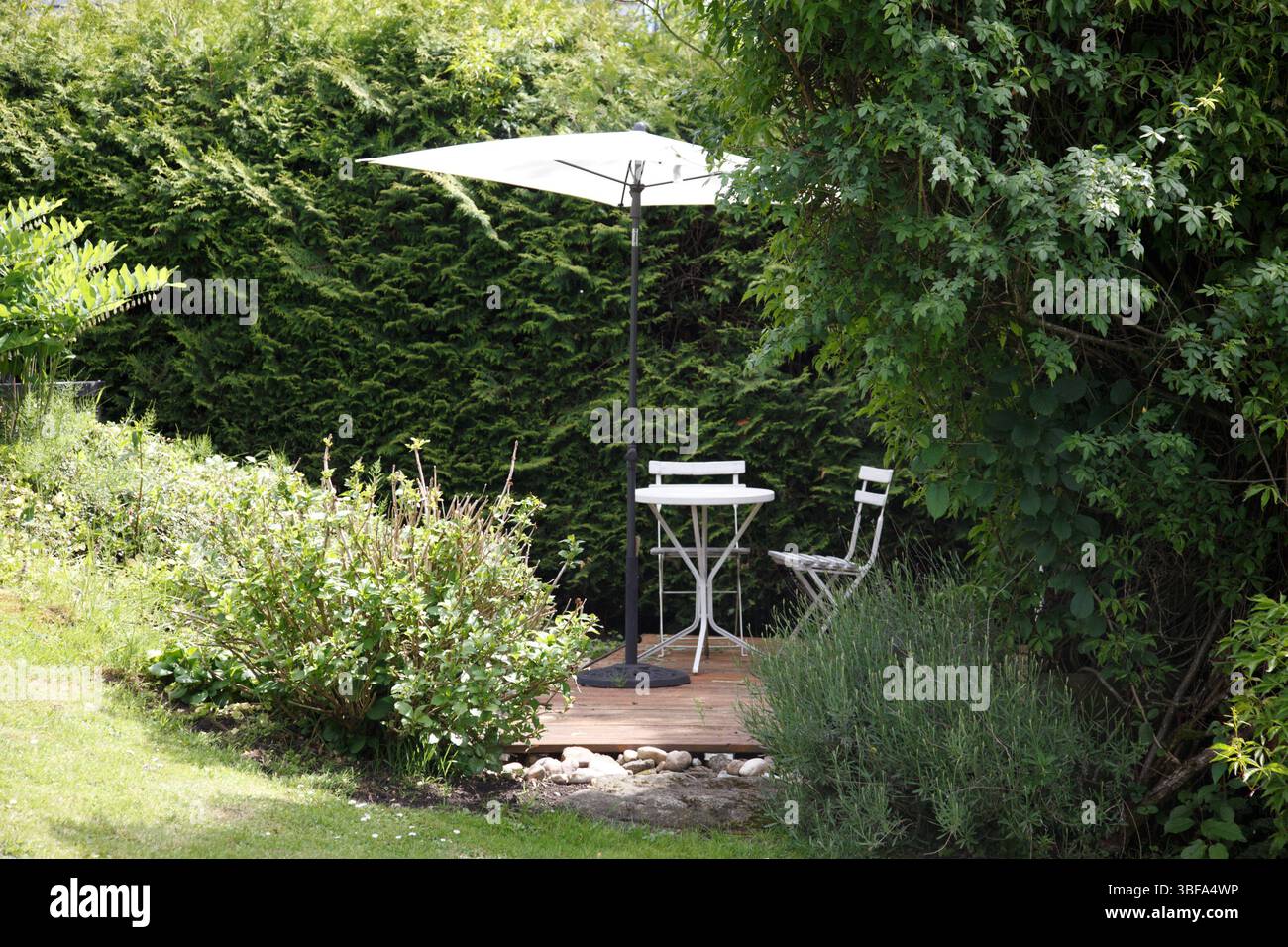 Sparen Sie Privatsphäre in einem romantischen Rückzugsort mit natürlicher Privatsphäre im Garten und einer Sitzgruppe und einem Sonnenschirm voll im Grünen. Foto Willy Matheisl Stockfoto