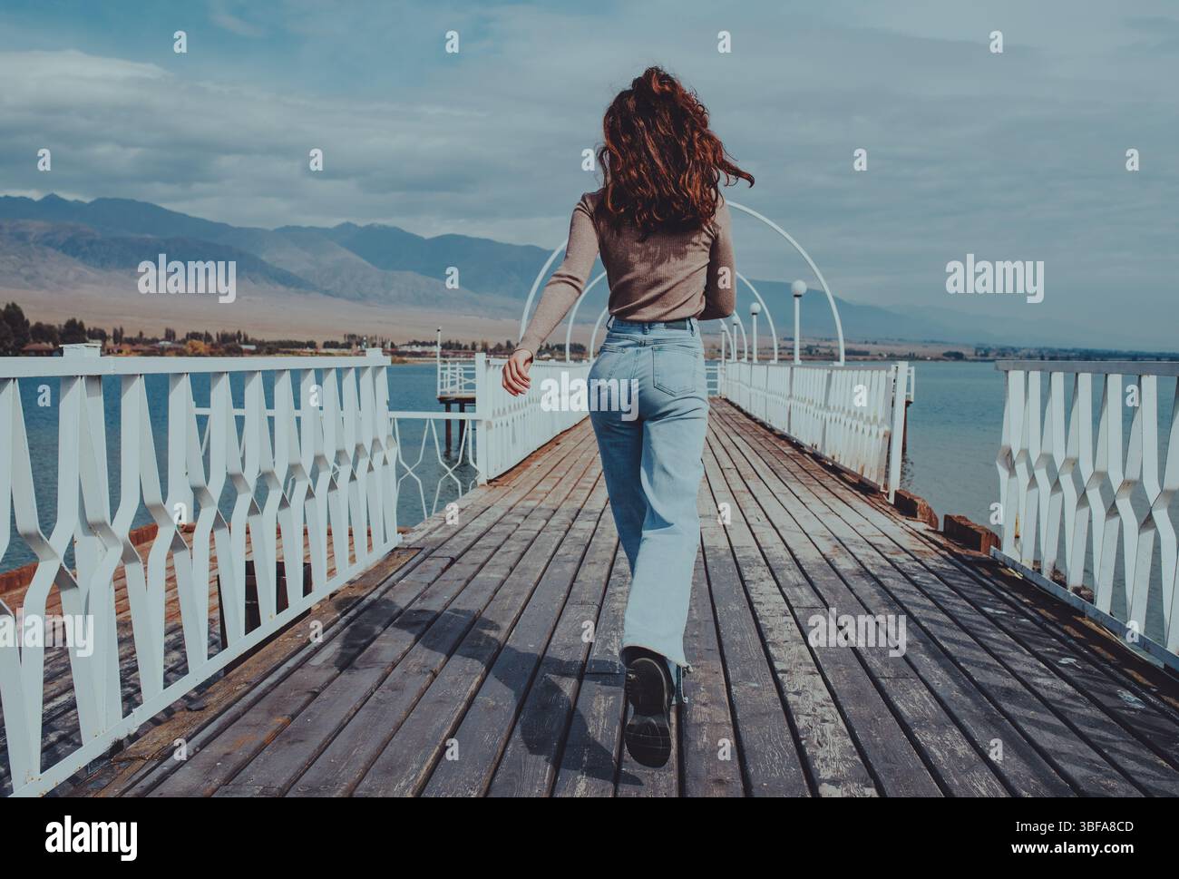 Frau, die am Sommertag auf der Brücke am Seeufer davonläuft Stockfoto