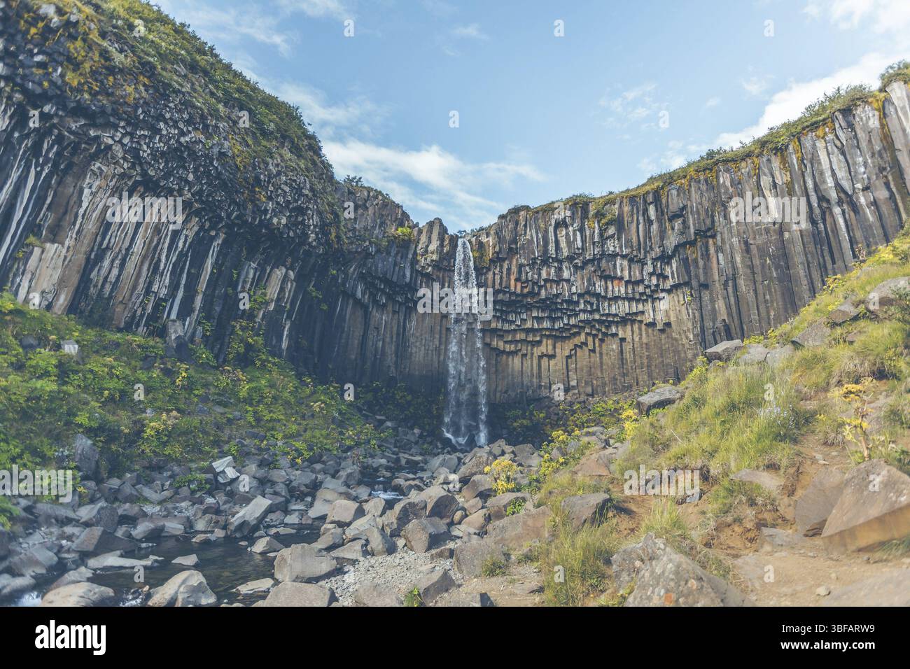 Wasserfall Svartifoss in Island unter einem blauen Himmel mit Wolken Stockfoto